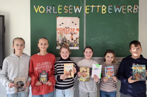 Fünf Mädchen und ein Junge stehen vor einer grünen Kreidetafel.